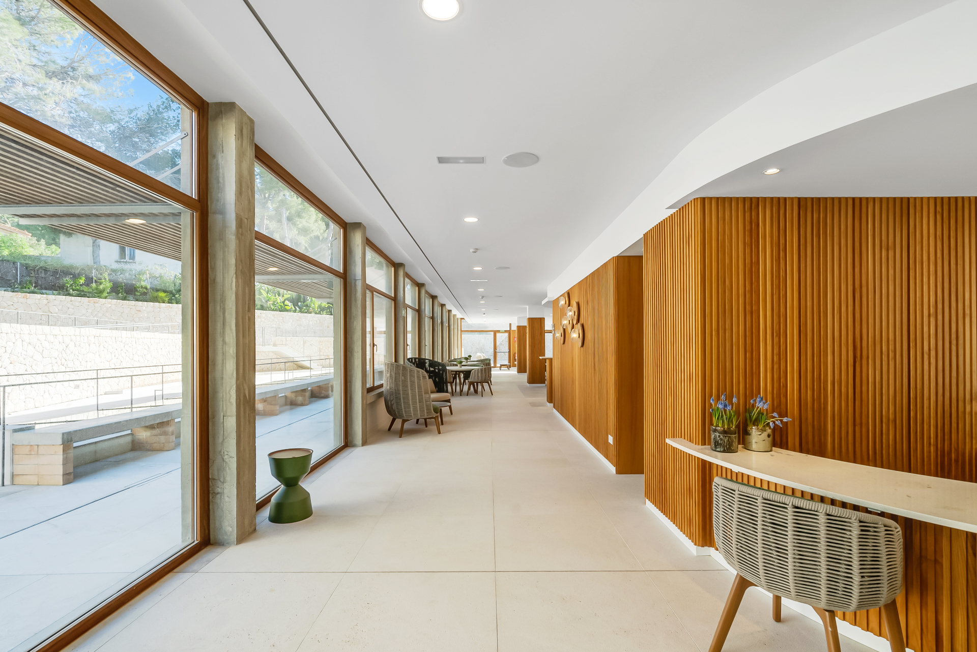 Sunlit corridor with floor-to-ceiling windows and timber walls