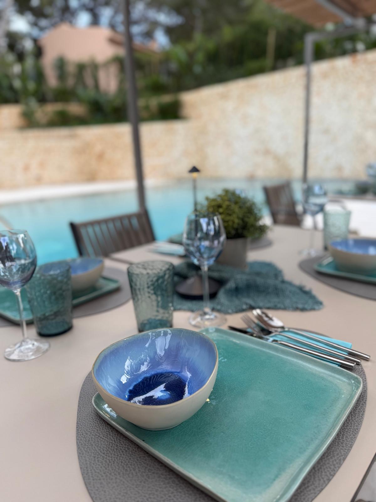 Poolside table set with ceramic tableware in blue and green